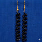 Black beaded earrings on a blue background