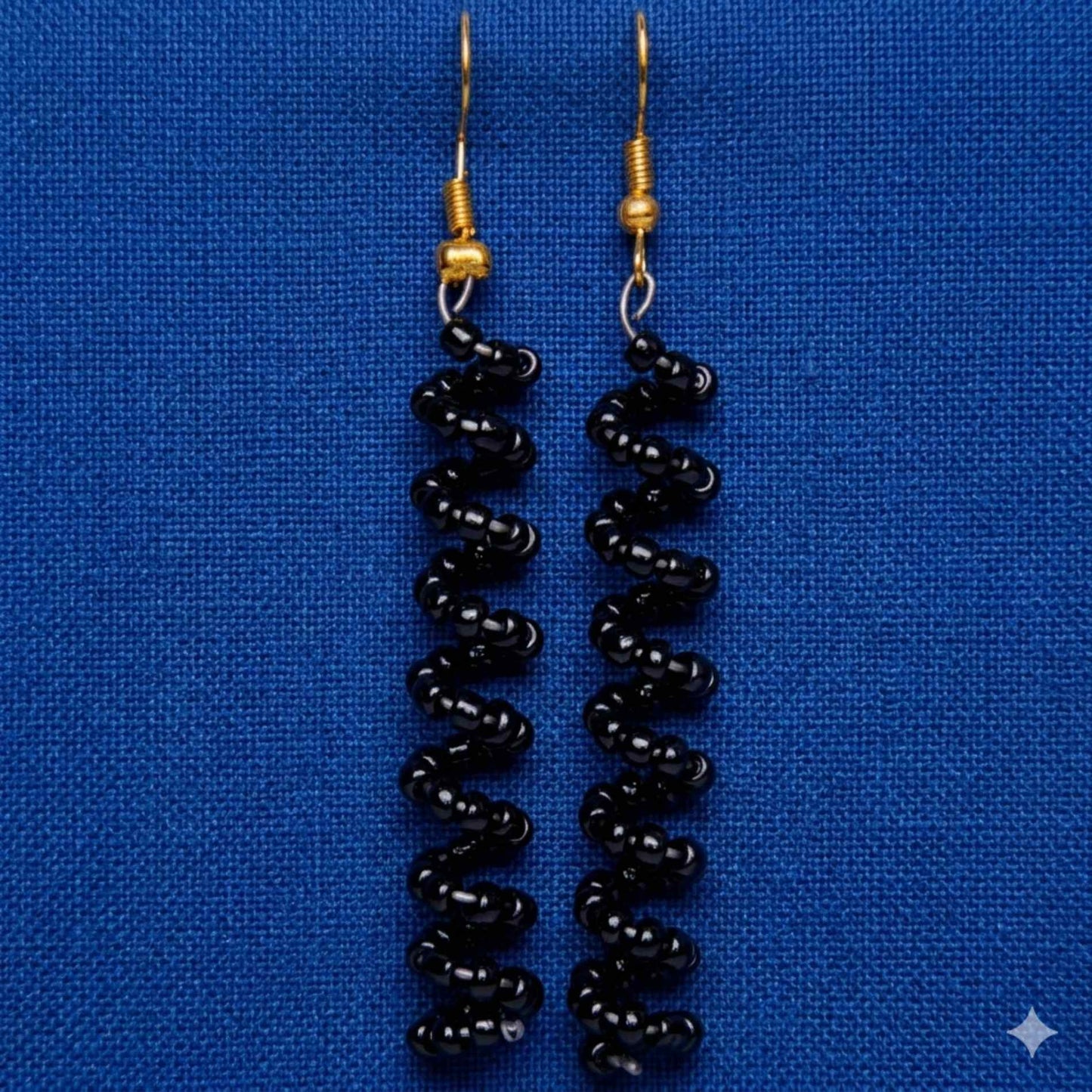 Black beaded earrings on a blue background