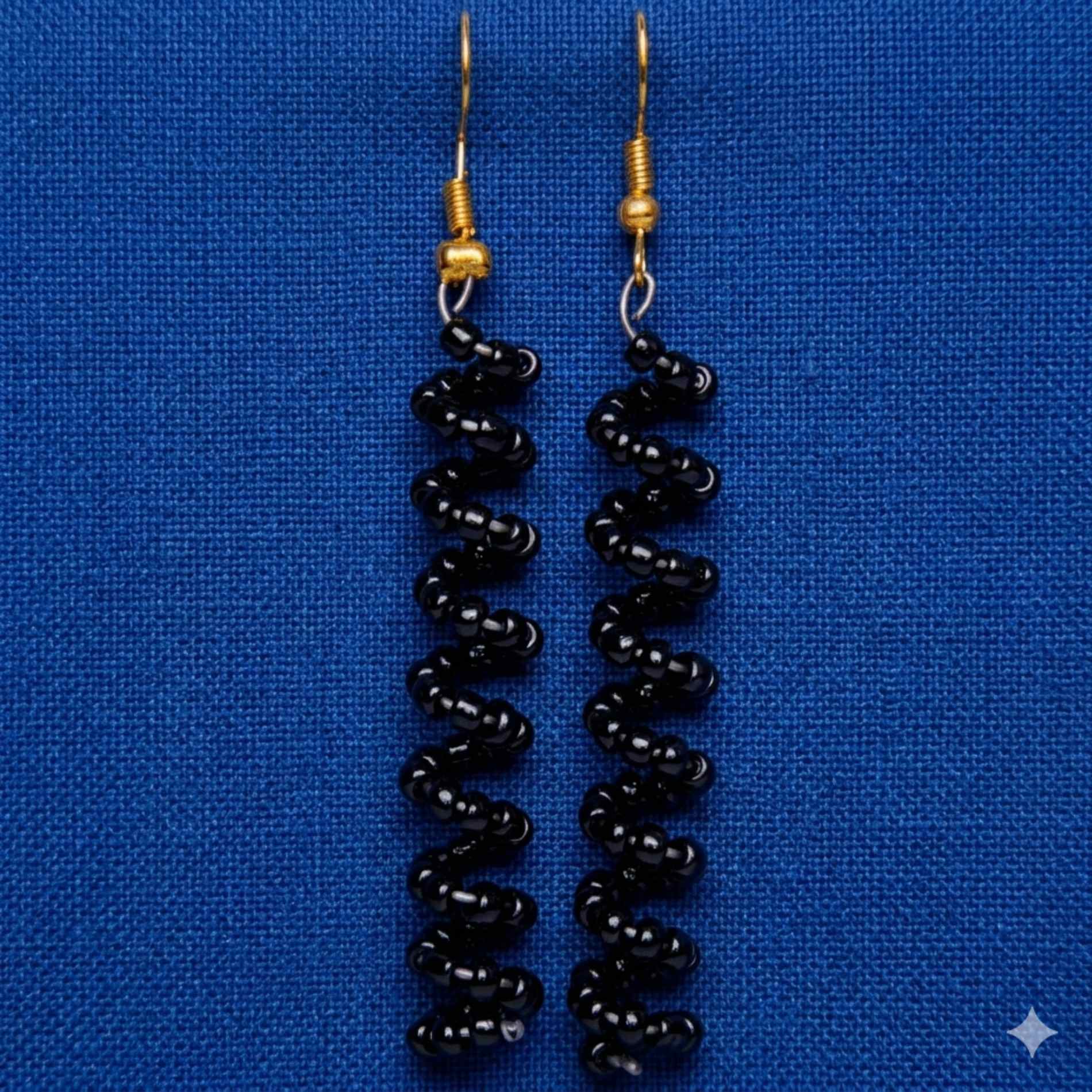 Black beaded earrings on a blue background