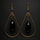 A pair of gold and black teardrop earrings on a black background.