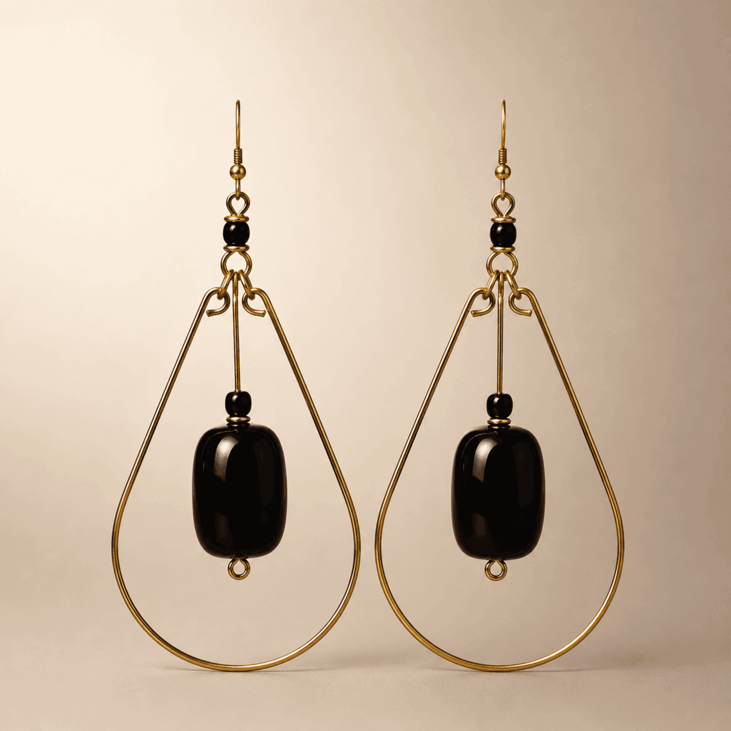 Gold teardrop earrings with a black bead in the middle.