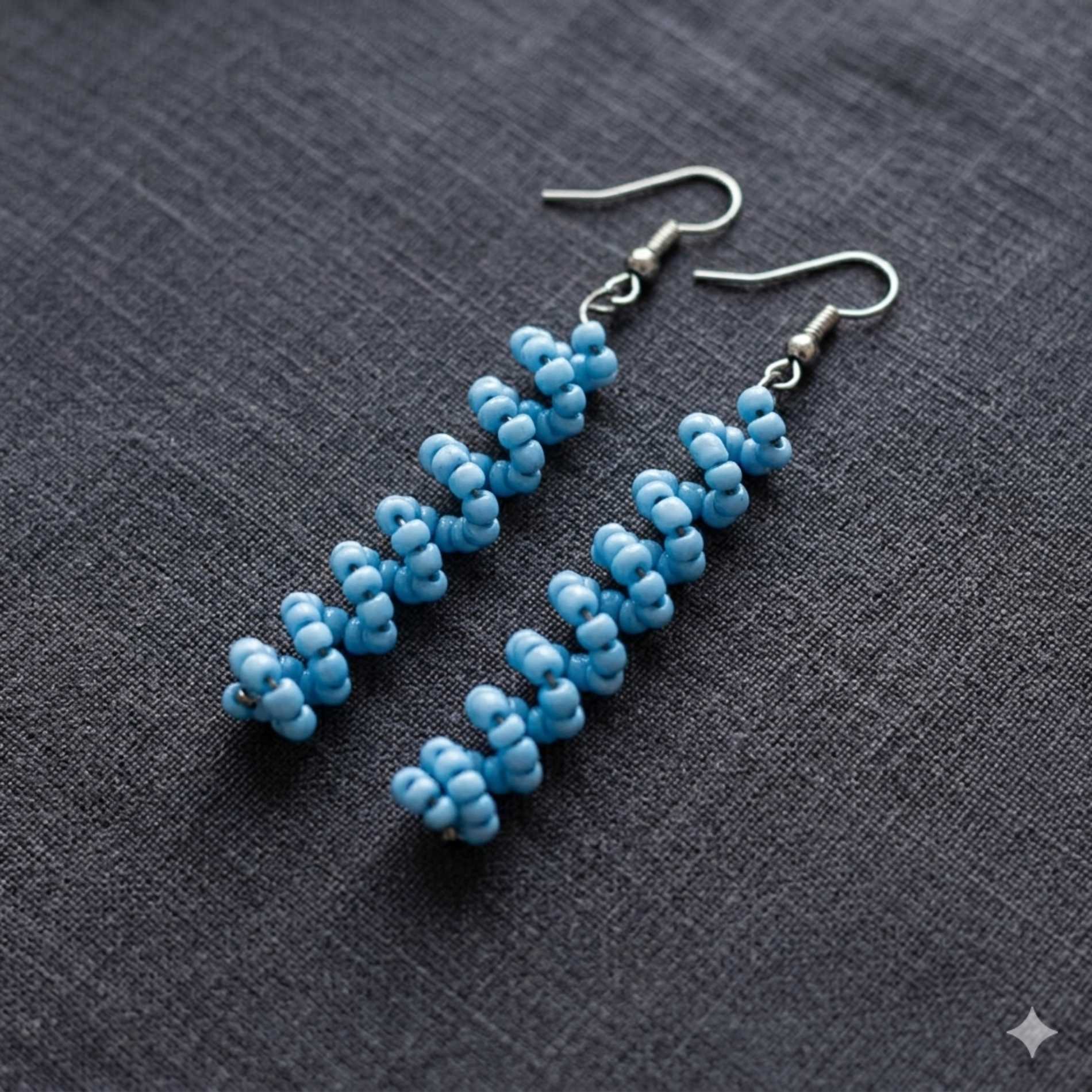Blue beaded earrings on a gray fabric background