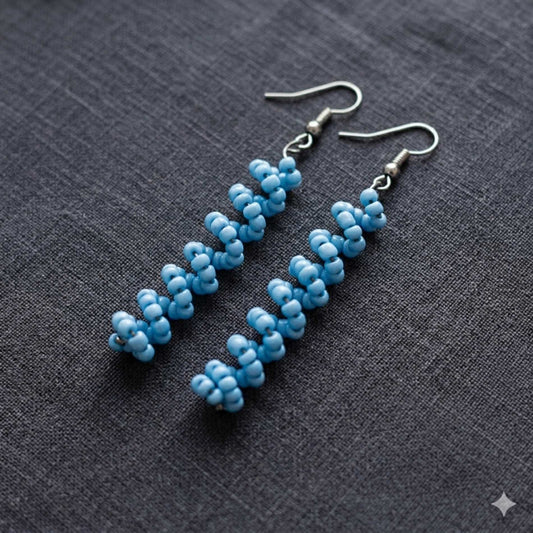 Blue beaded earrings on a gray fabric background