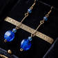 Gold earrings with blue beads on a black velvet background
