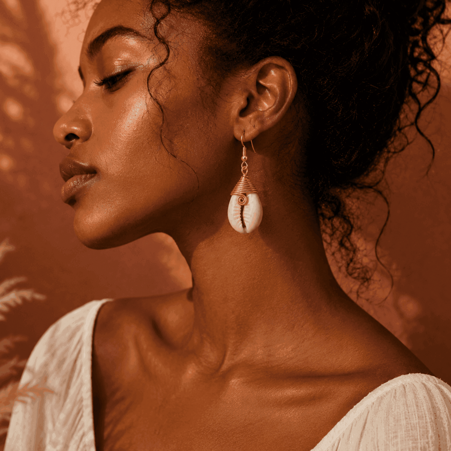 Woman wearing a shell earring with a warm-toned background