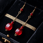 Gold earrings with red beads on a black velvet background