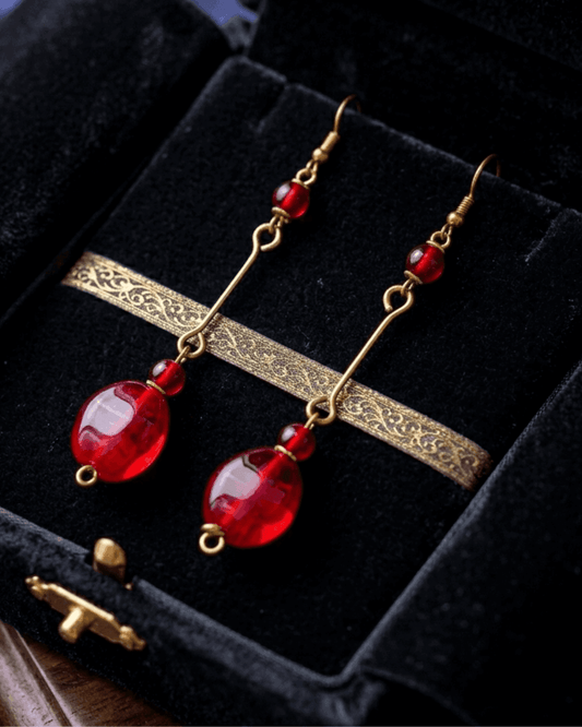 Gold earrings with red beads on a black velvet background