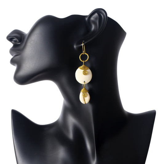 Handmade dangle earrings with a round, wire-wrapped camel bone disc stacked above a wire-wrapped natural cowrie shell.