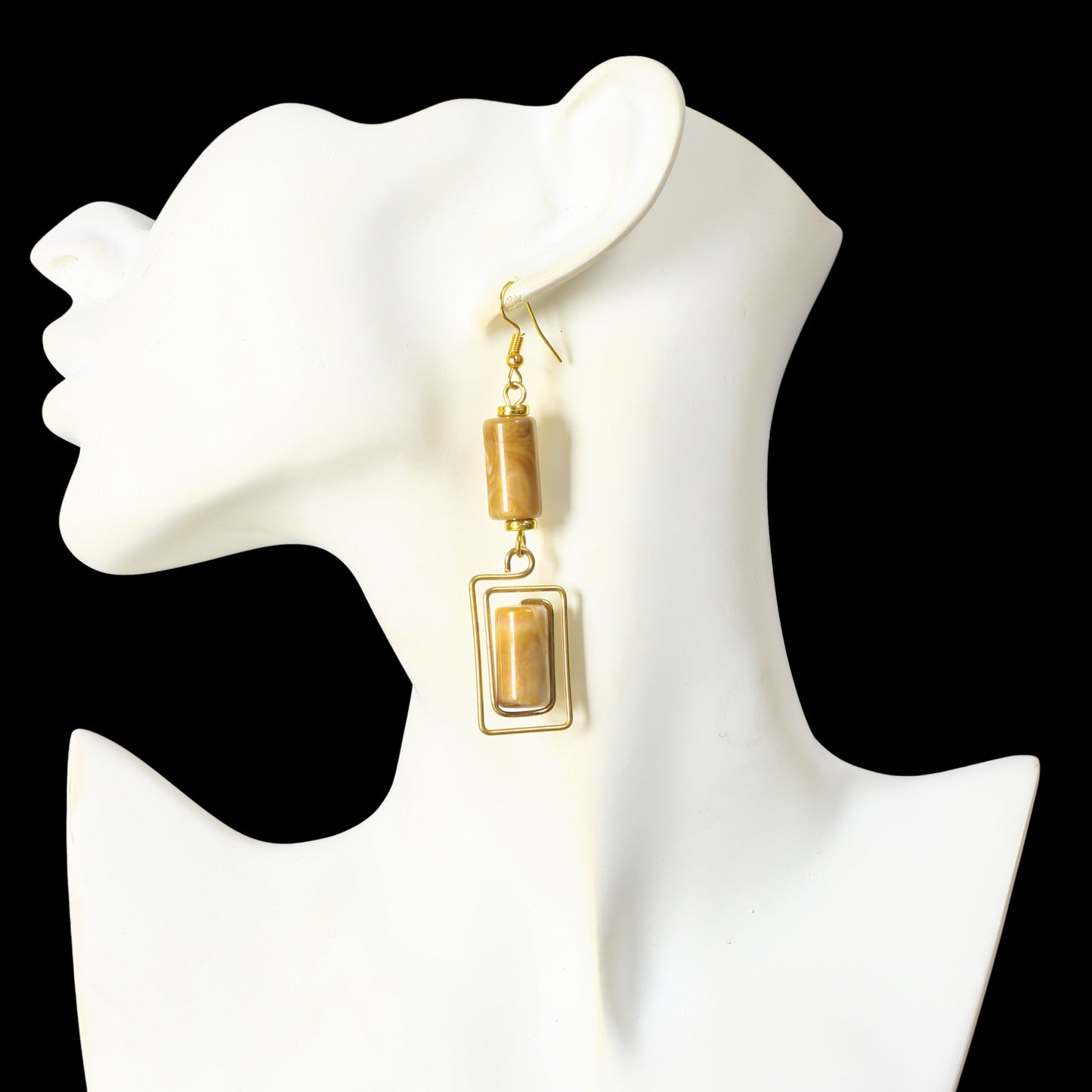Geometric gold dangle earrings with a marbled stone cylinder and a matching rectangular stone in a wire frame.