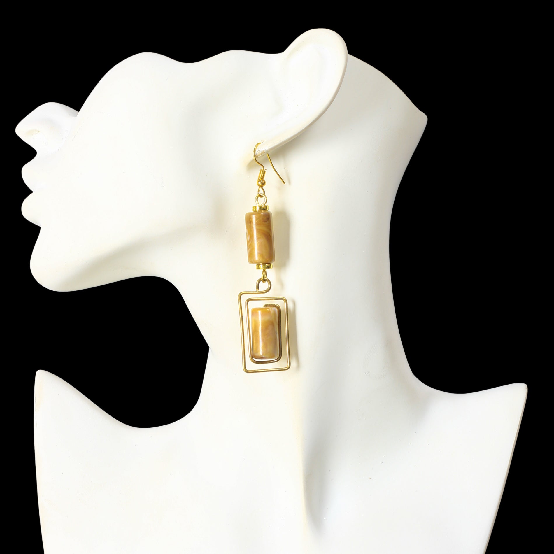 Geometric gold dangle earrings with a marbled stone cylinder and a matching rectangular stone in a wire frame.