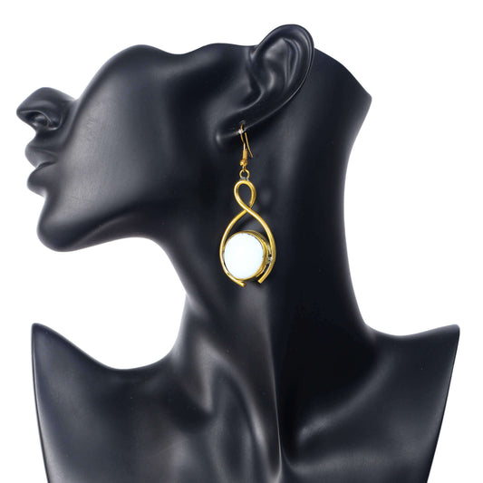 Gold infinity loop dangle earrings featuring a luminous white stone in the center.