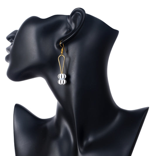 A pair of gold-plated U-shaped earrings dangling two round, black-and-white striped beads.