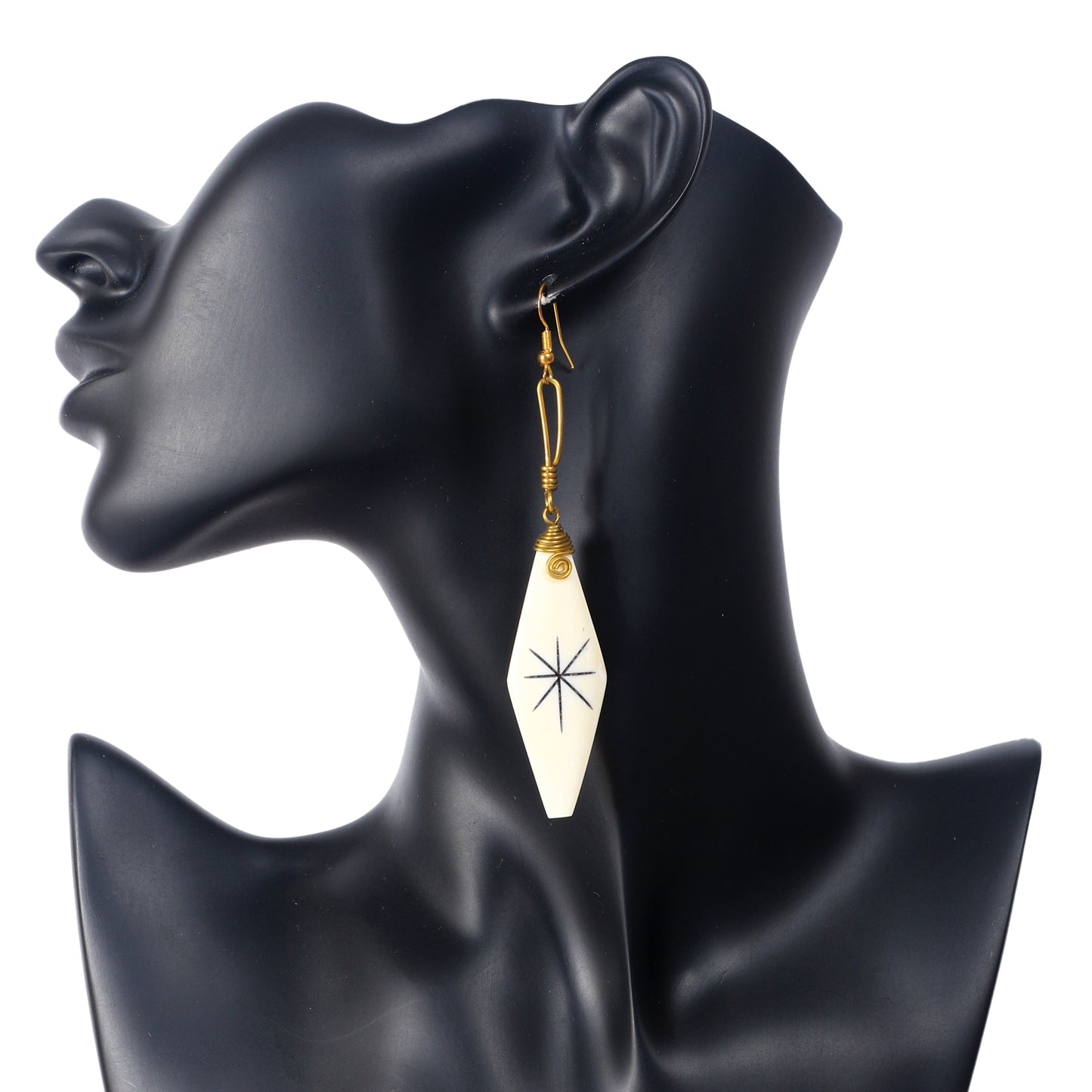 Handmade camel bone earrings in a diamond shape with a black etched starburst symbol and gold wire wrap.