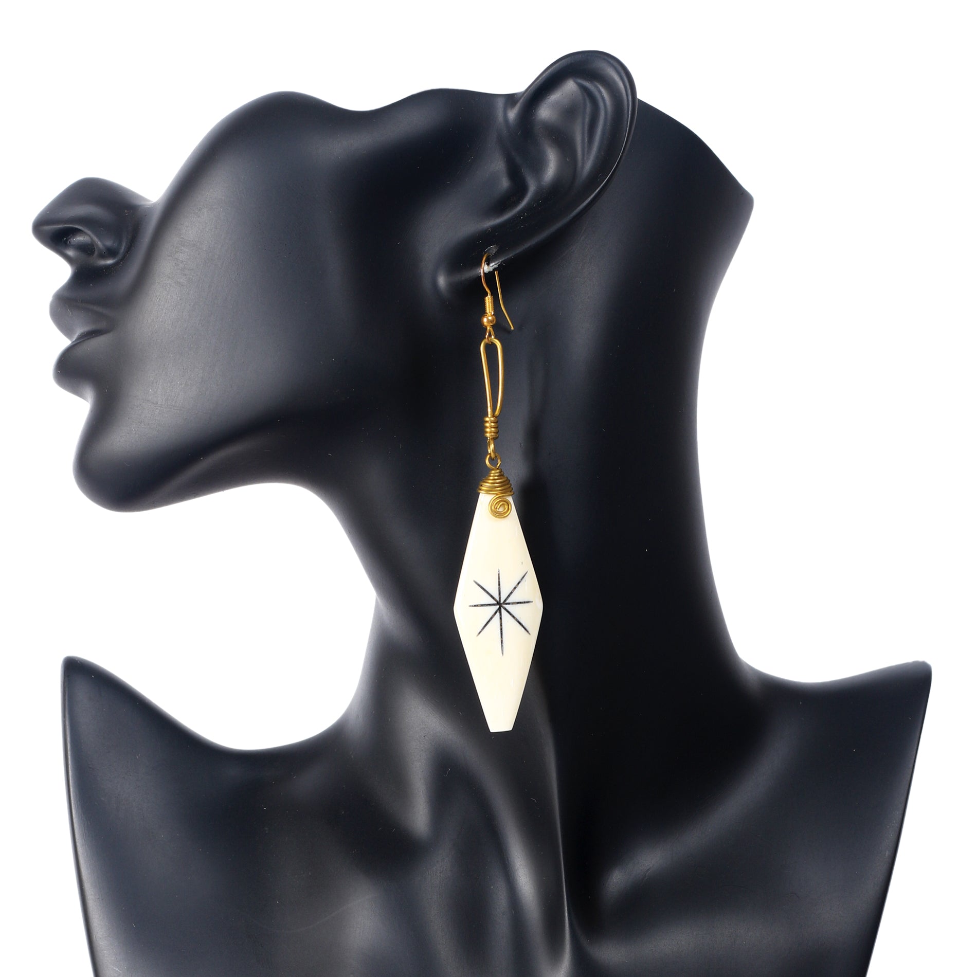 Handmade camel bone earrings in a diamond shape with a black etched starburst symbol and gold wire wrap.