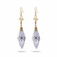 A pair of dangle earrings featuring white and gray camel bone pendants with a black starburst symbol.