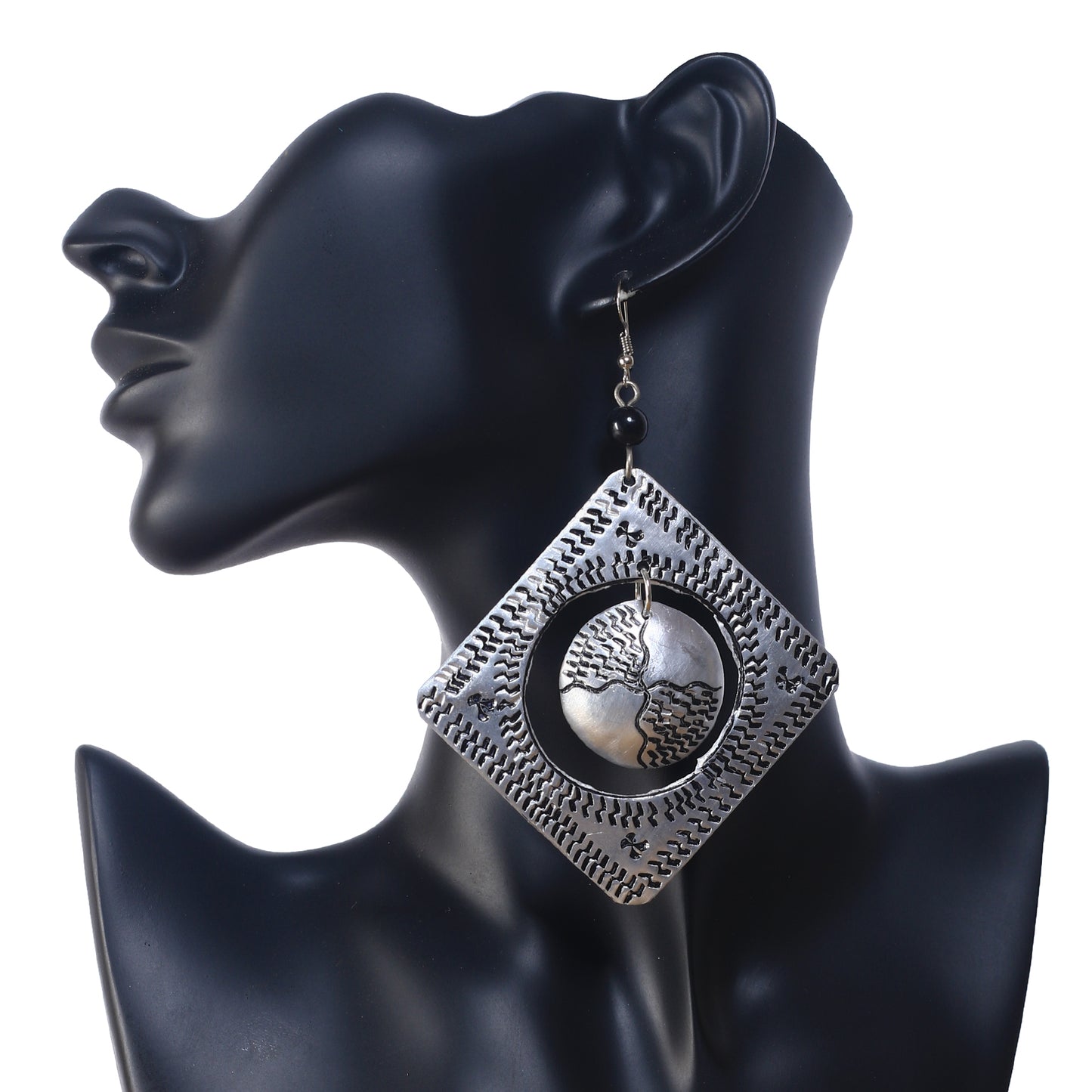 A pair of large, square, etched silver-plated earrings with a textured, free-moving disc in the center.