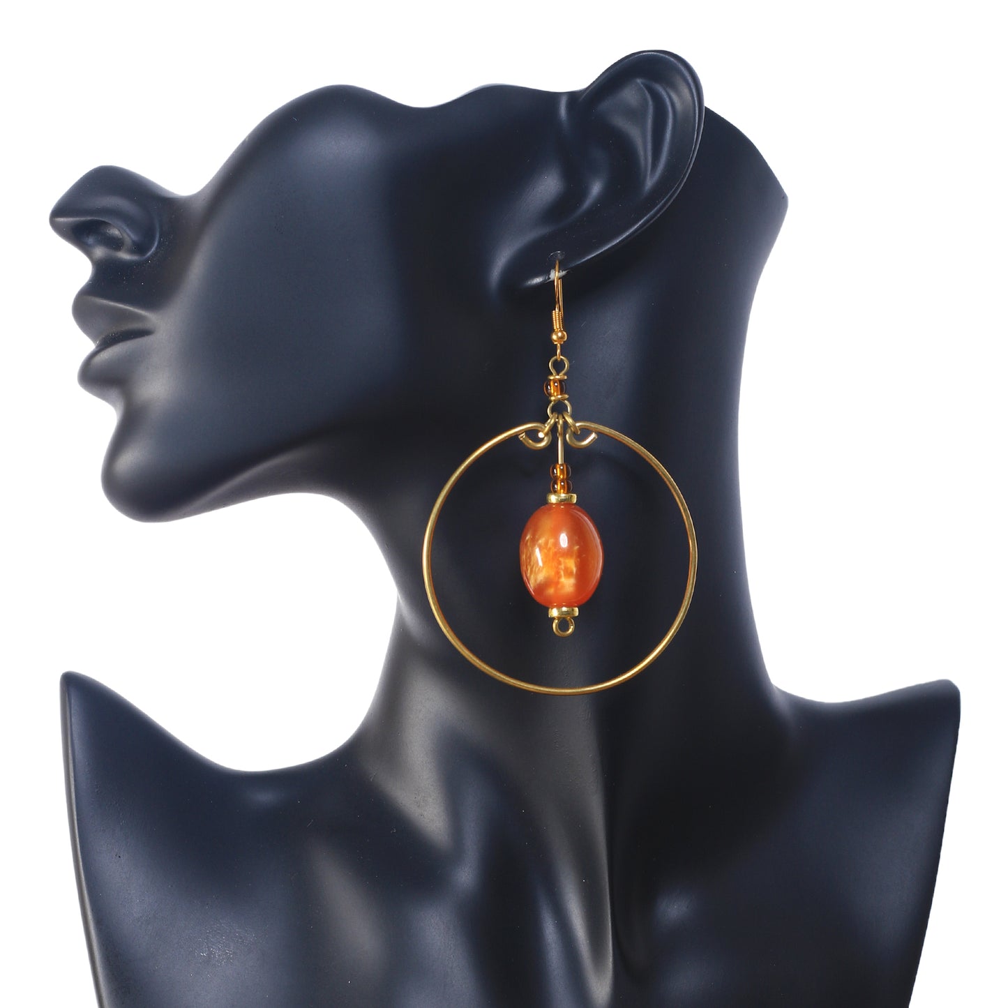 A pair of large, gold-plated hoop earrings with a marbled, amber-colored stone suspended in the center.