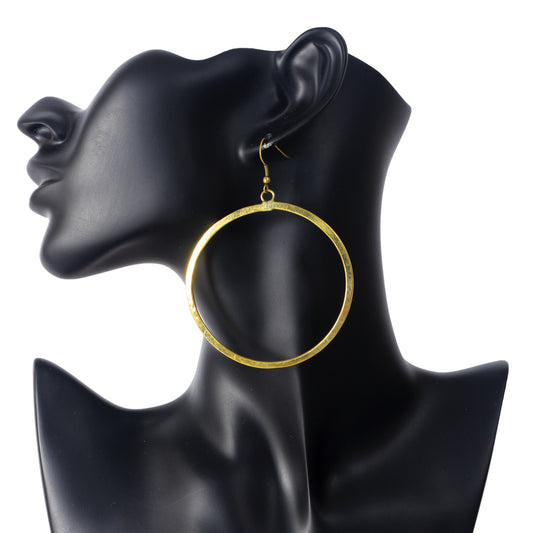 A pair of large, oversized, gold plated hoop earrings with a flat profile and a brushed matte finish.