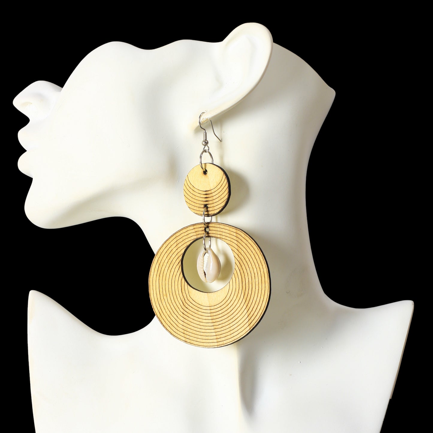 Large wooden statement earrings with an etched concentric ring pattern and a natural cowrie shell center.
