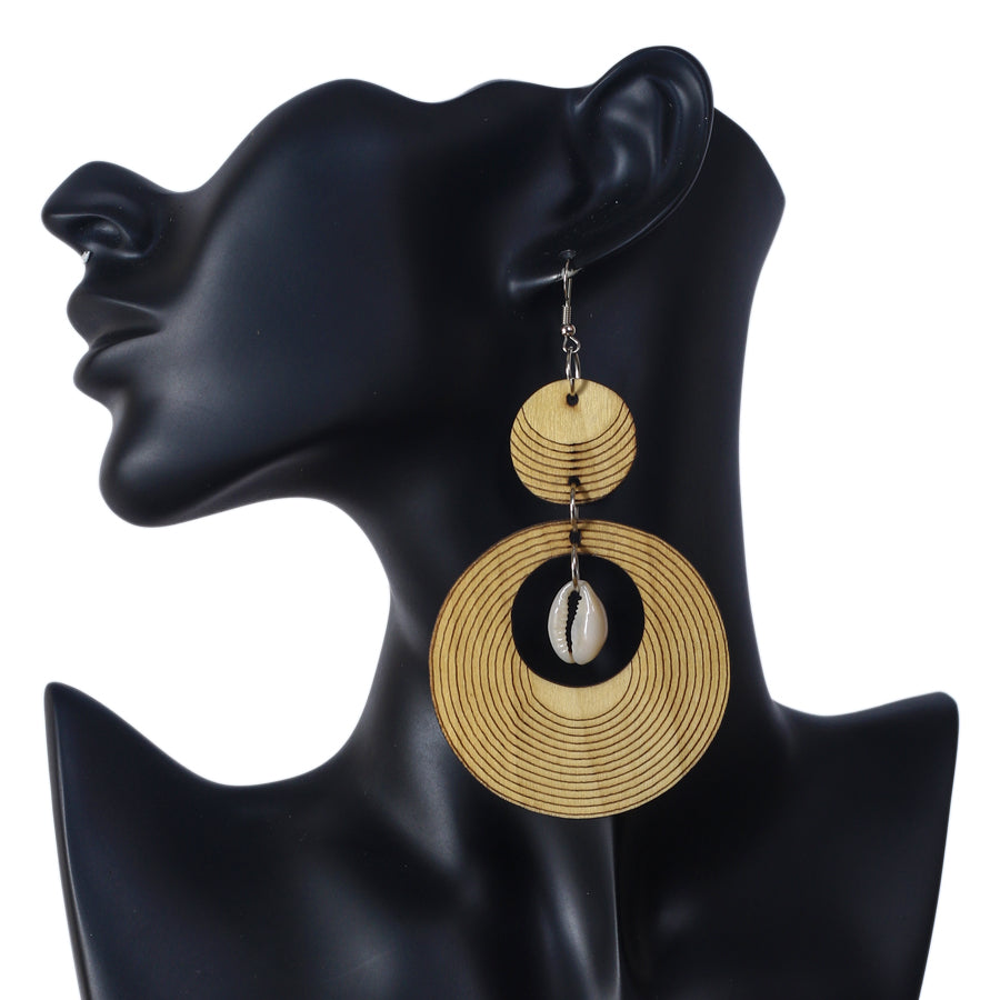 Large wooden statement earrings with an etched concentric ring pattern and a natural cowrie shell center.