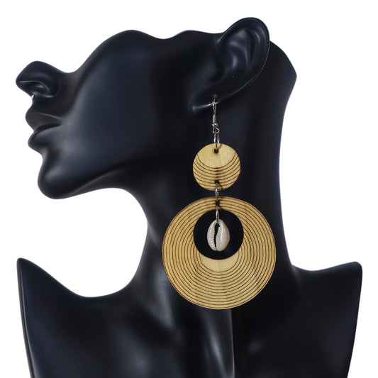 Large wooden statement earrings with an etched concentric ring pattern and a natural cowrie shell center.
