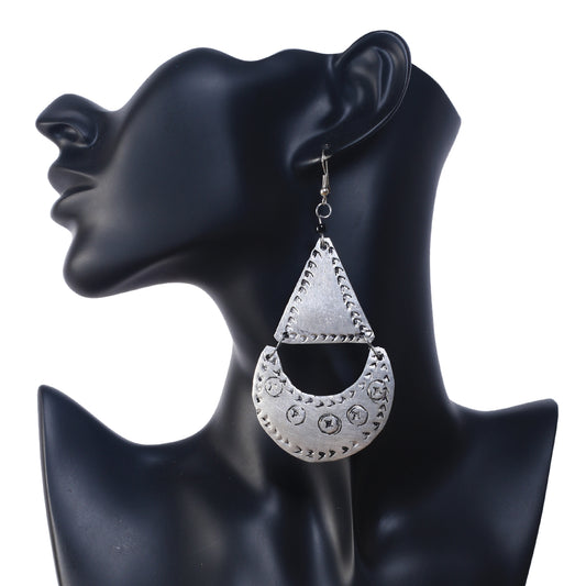 A pair of large, silver-plated geometric earrings featuring an etched triangle and a stamped crescent drop.