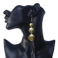Long gold-plated dangle earrings with three stacked, hammered discs and a black bead accent.