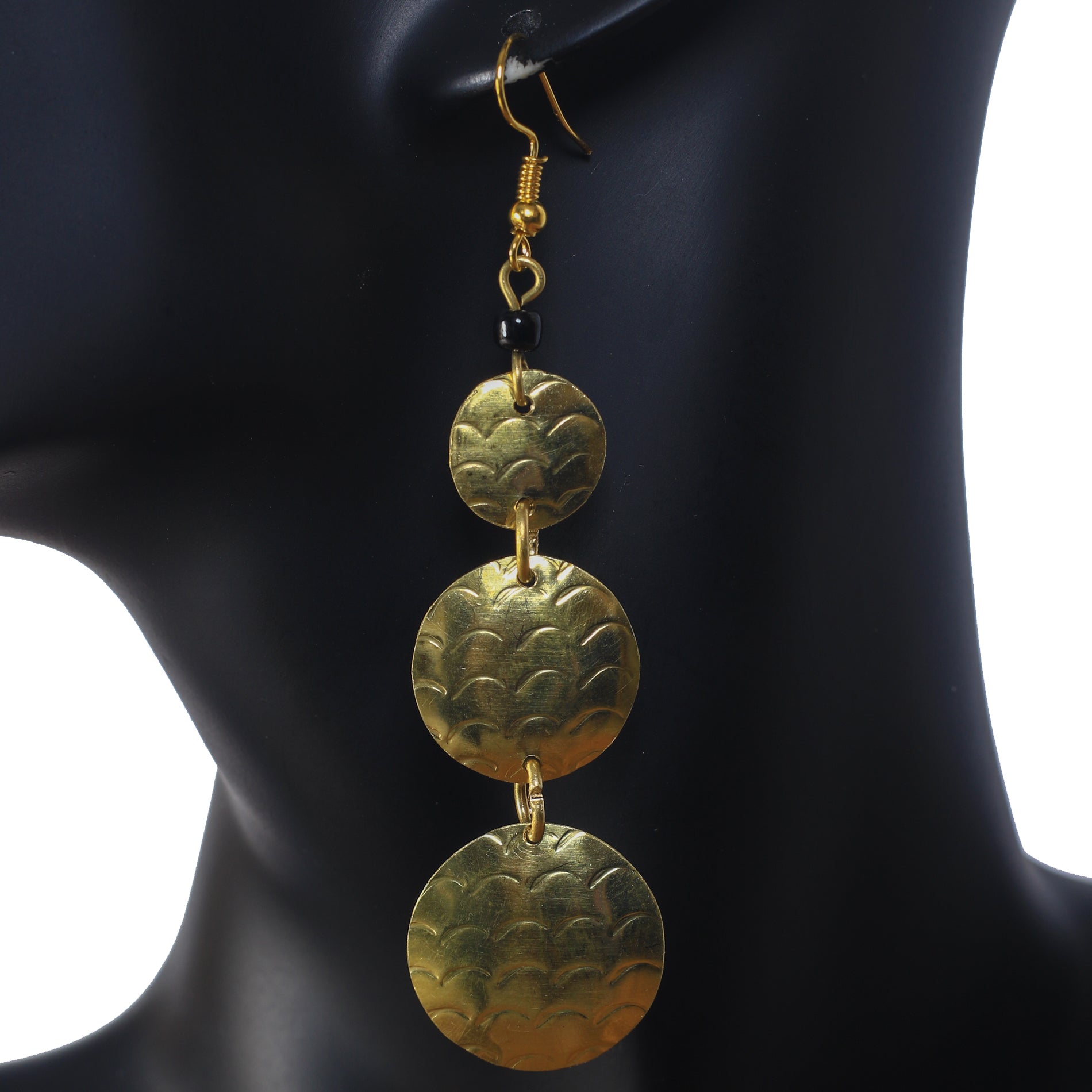 Long gold-plated dangle earrings with three stacked, hammered discs and a black bead accent.