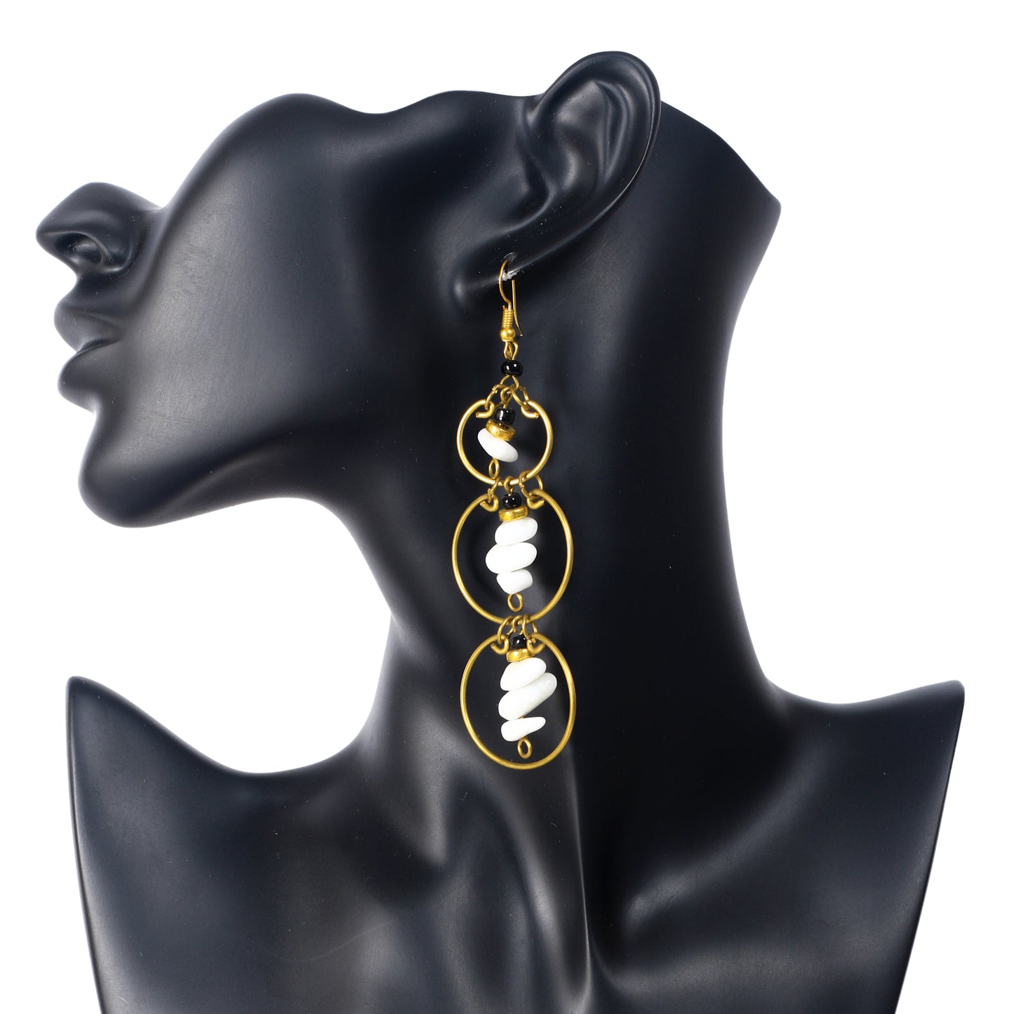 Long gold-plated earrings with three stacked rings, each holding a central dangle of white stone chips and black beads.