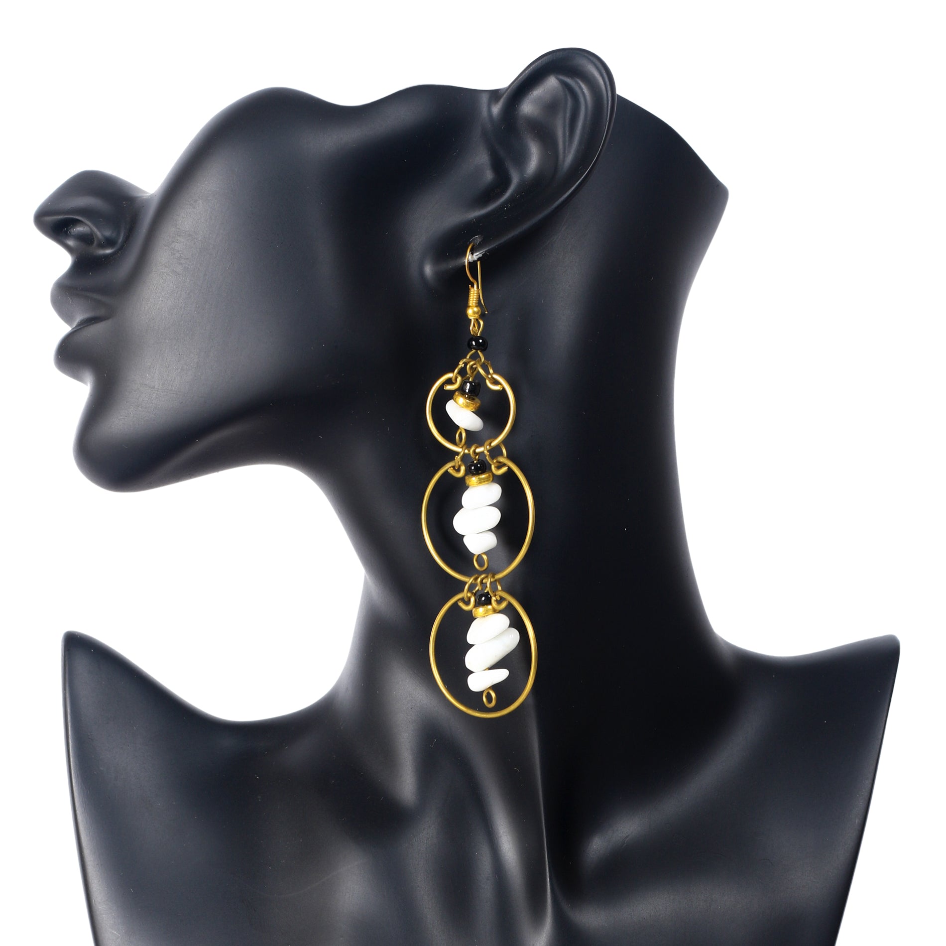 Long gold-plated earrings with three stacked rings, each holding a central dangle of white stone chips and black beads.