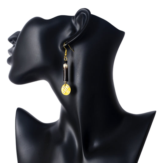 Long gold dangle earrings featuring a porcupine quill and a bright yellow disc with a stamped pattern.