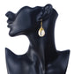 Wire wrapped shell earrings on a black mannequin bust with a white background